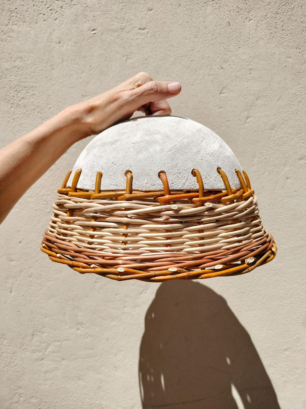 Aquest és un taller on fusionarem dues tècniques artesanes que tracten amb materials naturals. Treballarem amb la ceràmica i la cistelleria per crear una làmpada. Aprendrem a dissenyar per saber com modelar i teixir amb fibres vegetals locals una sola peça creativa i funcional. Amb l'Eia començarem a pensar l’estructura base de la làmpada i a donar-li forma a través de les tècniques bàsiques del modelatge utilitzant diferents fangs de colors. Continuarem amb la peça ja cuita amb el Roger de Cistelleria Esberla. Teixint amb fibres vegetals locals com ara diferents varietats de vímet, canya i balca per donar la forma final a la nostra làmpada.